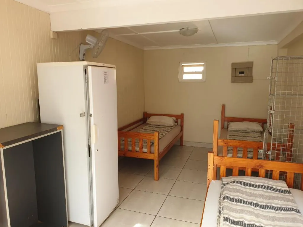 Dorm room with three wooden bunk beds, a tall fridge and tiled floor