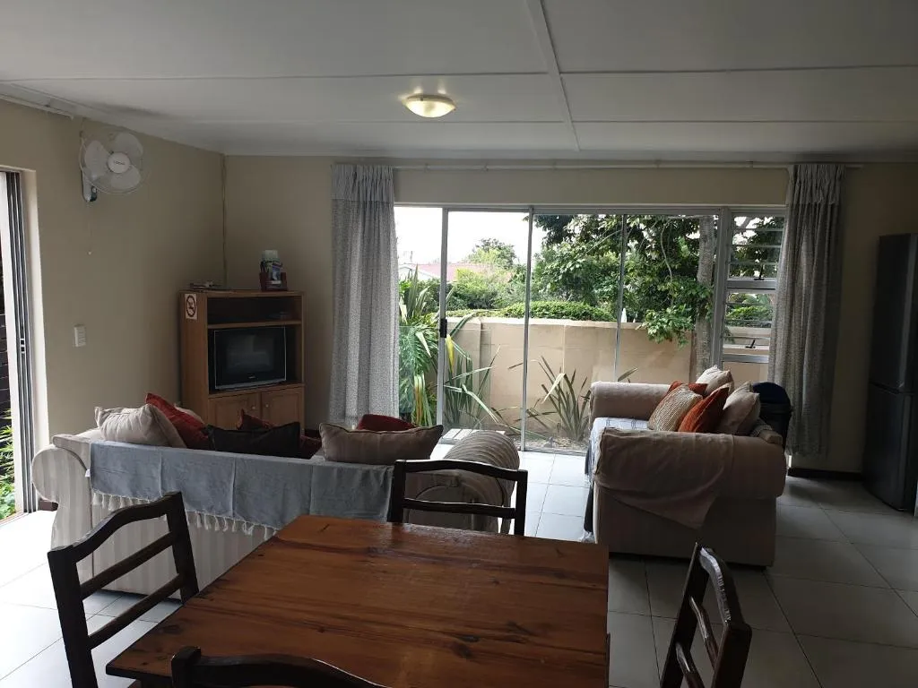 Lounge and dining area with a wooden table, sofas and sliding doors onto a leafy garden