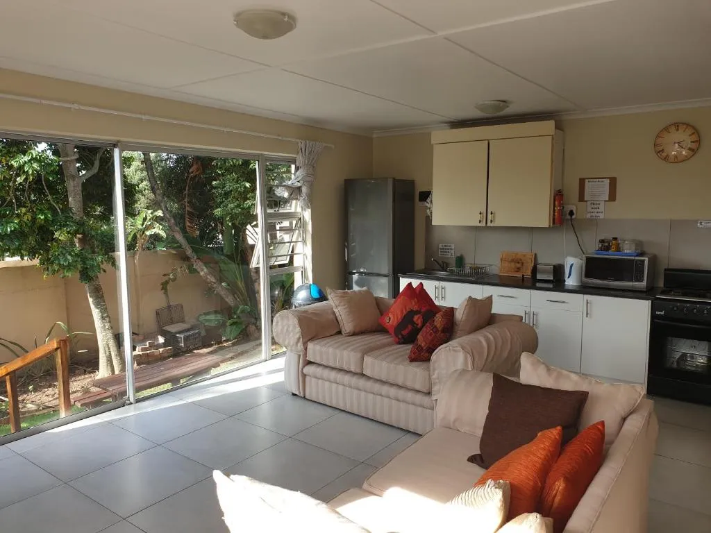 Open-plan lounge and kitchen with cream sofas, a fridge and sliding doors onto the garden