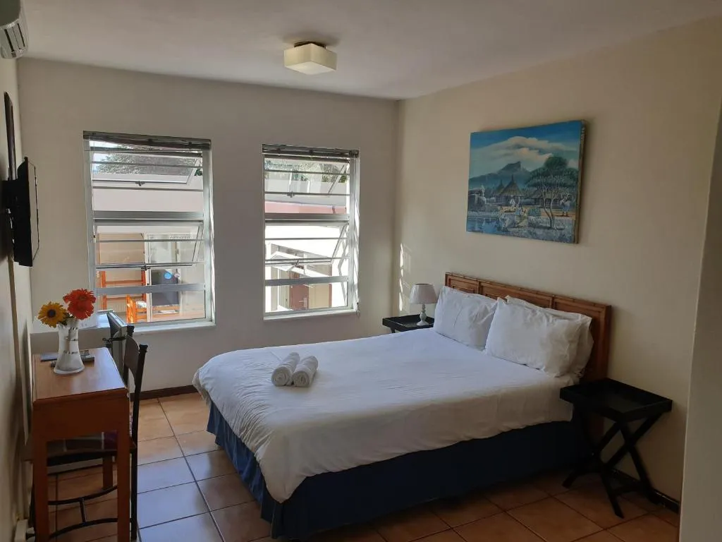Private double room with a wooden headboard, rolled towels and a framed African landscape painting