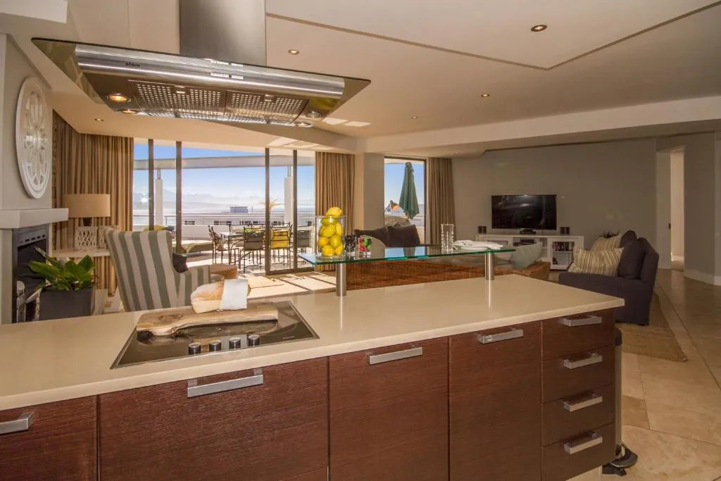 Dark wood kitchen with an island hob, extractor hood, and glimpse of the terrace beyond
