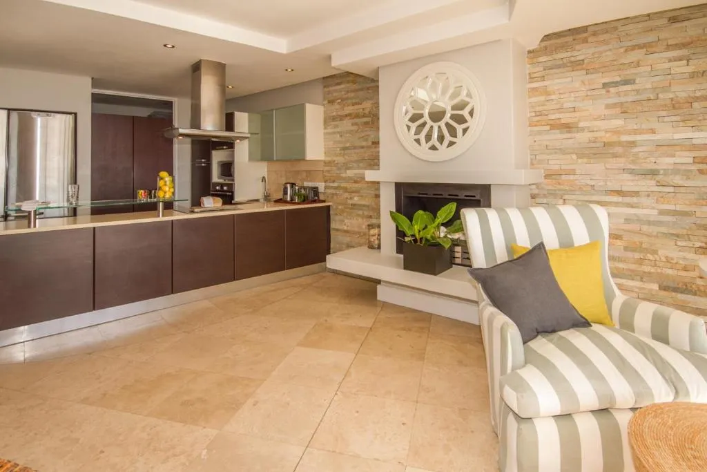 Lounge with a built-in fireplace, striped armchair, and exposed stone feature wall