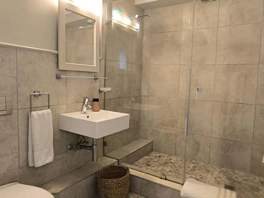 Bathroom with a walk-in glass shower and floating basin, finished in stone-look tile
