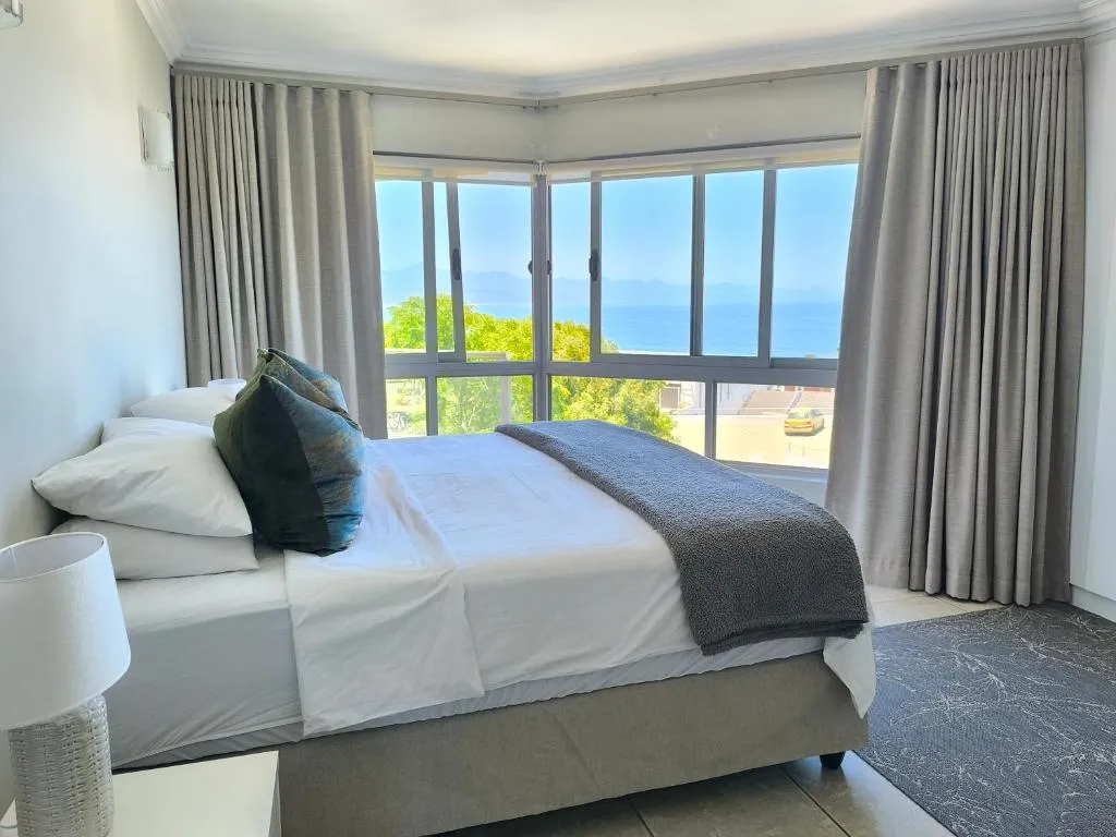 Corner bedroom with a bay window framing the sea and coastal road below