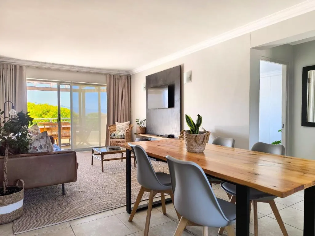 Dining and living area with a wall-mounted TV and glass doors opening to the terrace
