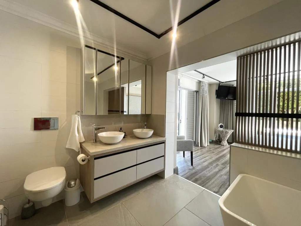 Ensuite with a double vessel-sink vanity and mirrored cabinets, opening onto the lounge beyond