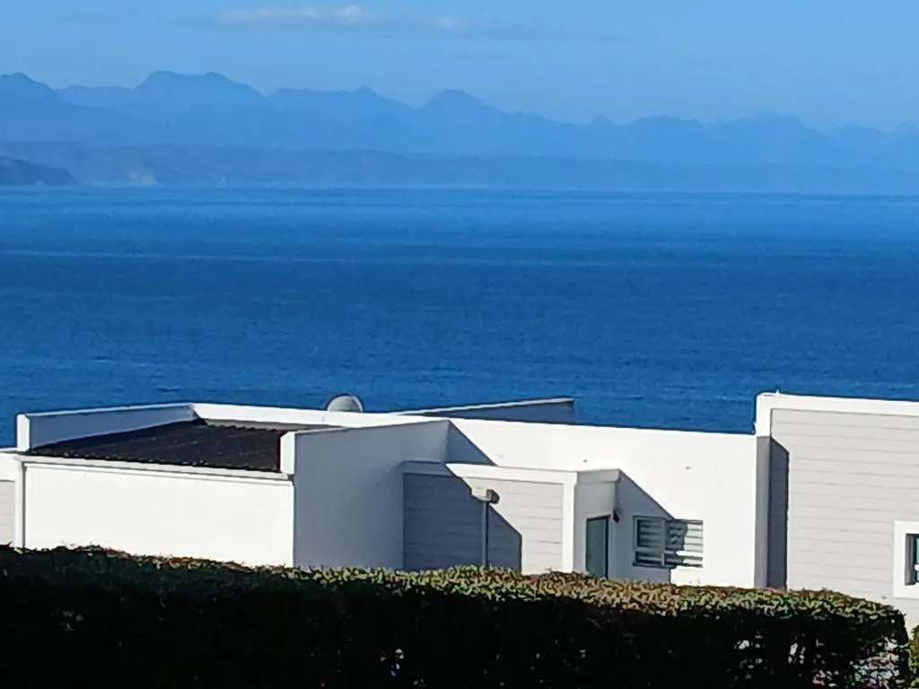 Ocean and mountain view over a neighbouring rooftop from the apartment block