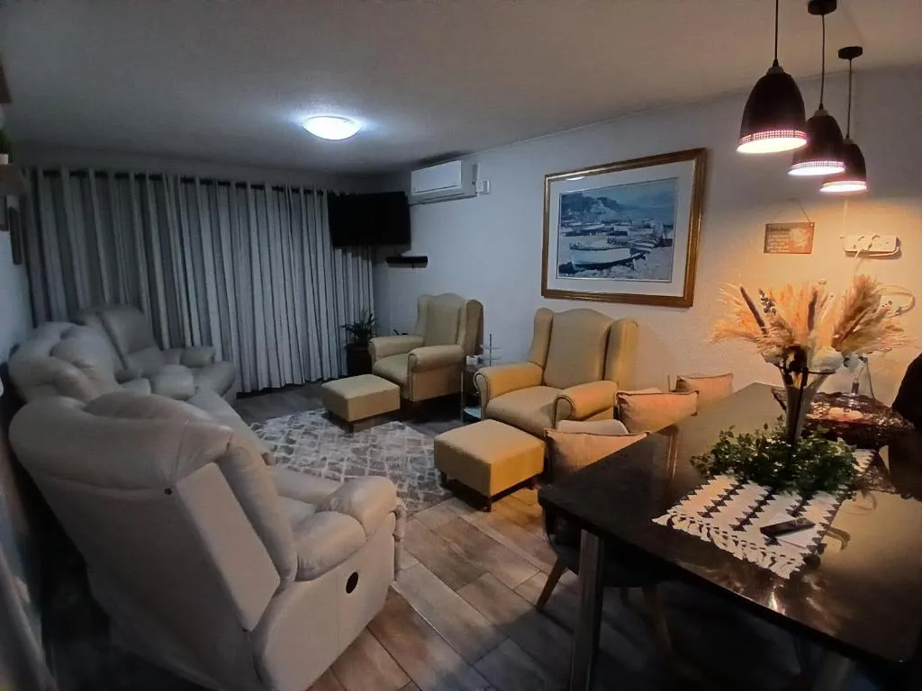 Second lounge with grey leather reclining sofas and a dining table beneath pendant lights