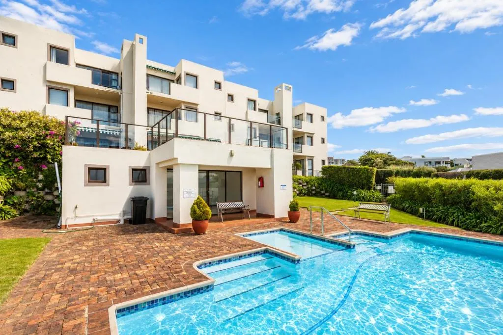 Apartment block exterior with communal jacuzzi and swimming pool on the grounds