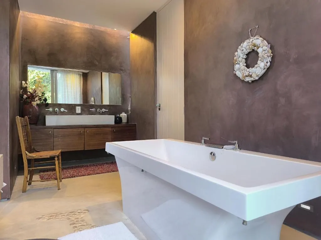 Freestanding bathtub beside a dark wood double-basin vanity in an en-suite bathroom