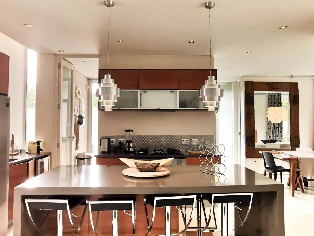 Kitchen island with bar stools, pendant lighting and dark wood cabinetry