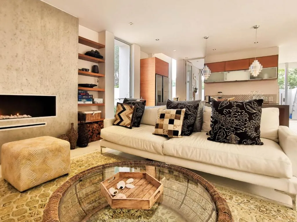 Living room with a built-in lit fireplace, patterned cushions and a round glass coffee table