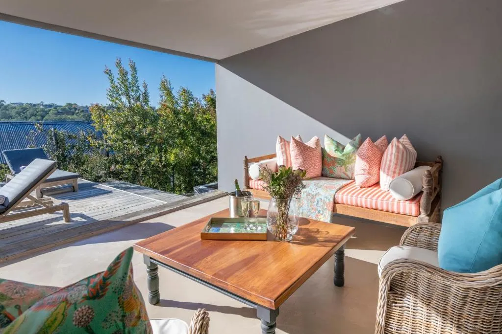 Covered patio lounge with striped cushions and wicker chairs overlooking treetops and rooftops