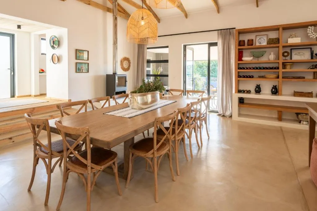 Dining room seating ten at a long wooden table beneath rattan pendant lights and a wood burner
