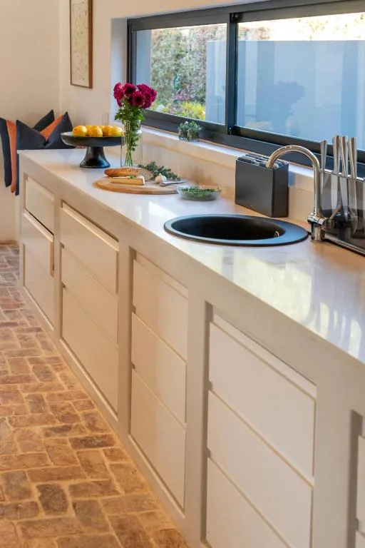 Kitchen counter with white cabinetry, a black sink and a window onto the garden