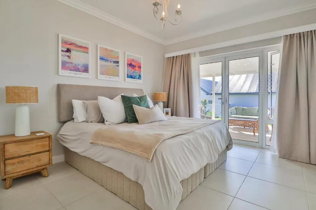 Bedroom with a king bed, colourful artwork and sliding doors onto a covered patio