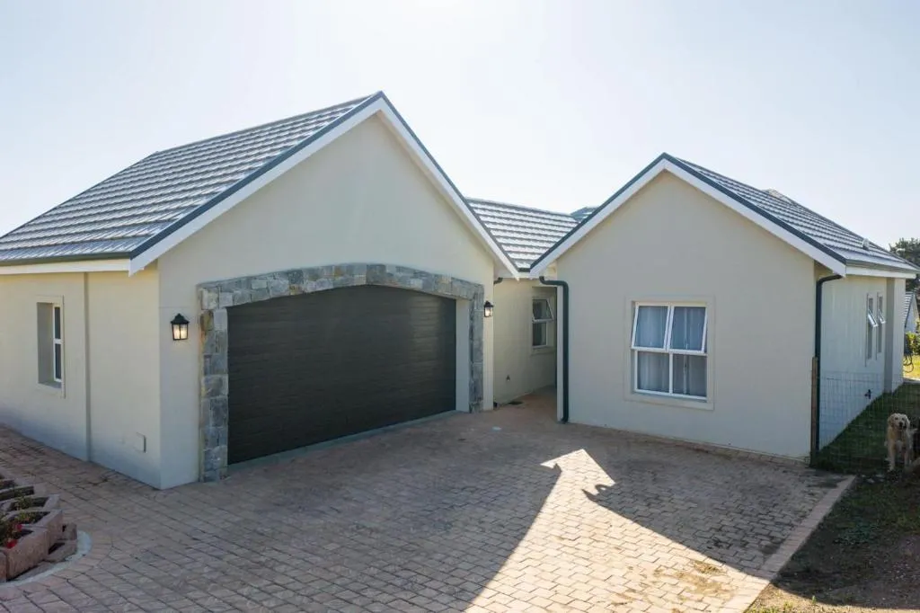 Double-storey house exterior with a stone-clad double garage and a dog on the driveway