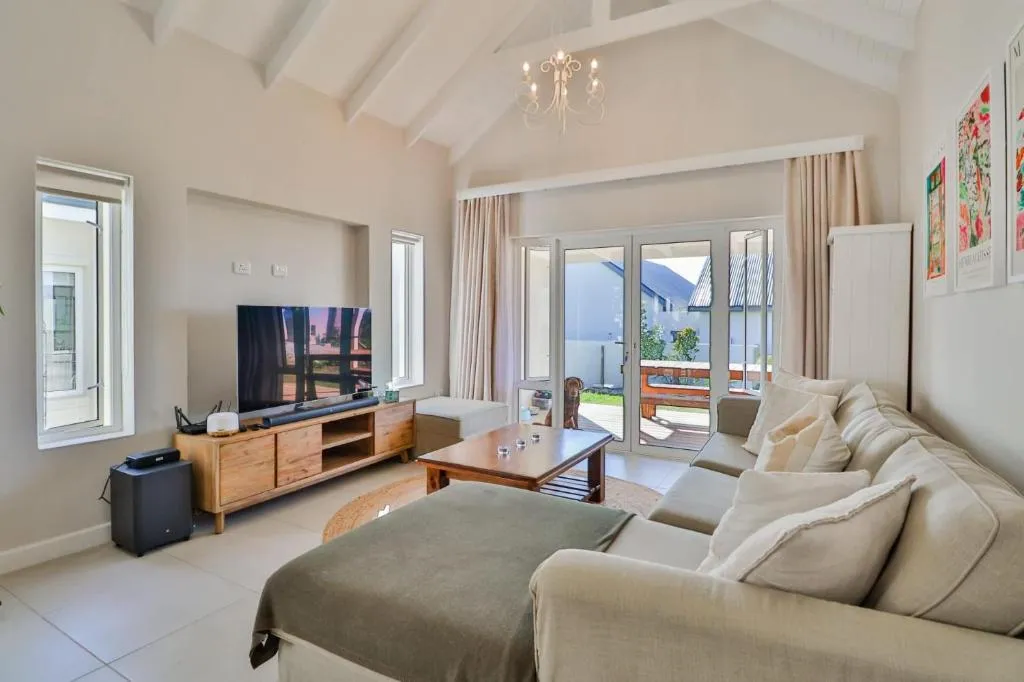 Vaulted-ceiling living room with a beige sectional sofa, TV console and patio doors