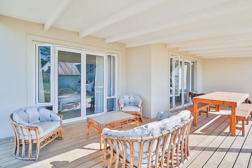 Covered veranda with wicker lounge seating and a wooden dining table