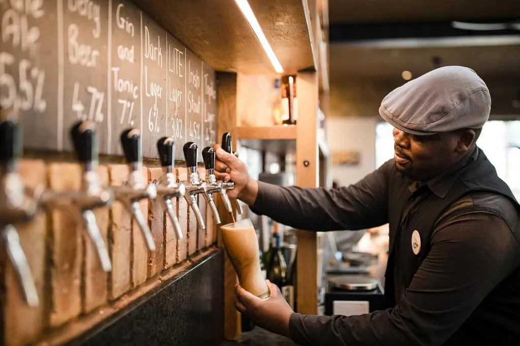 Bartender pouring a draught beer at the hotel's brick-fronted tap bar