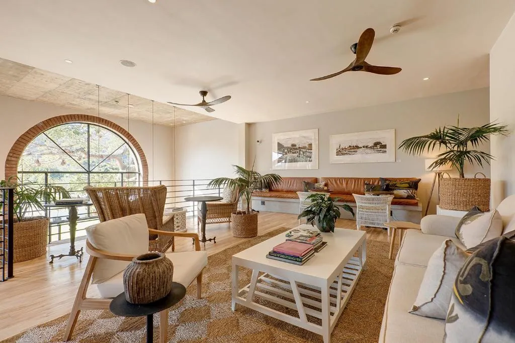 Upstairs lounge with a large arched window, leather bench seating and potted palms