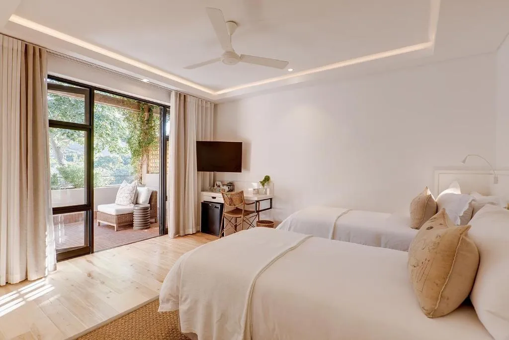 Twin bedroom with sliding doors onto a private balcony shaded by trees