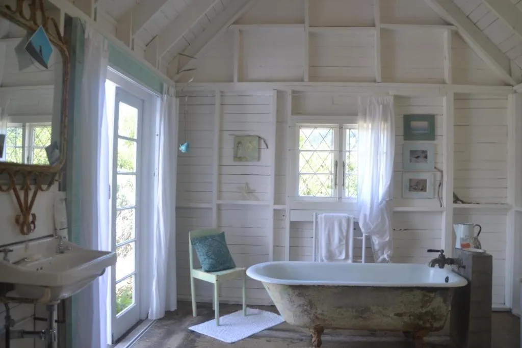 Freestanding vintage clawfoot bathtub in a white shiplap-lined bathroom with garden light