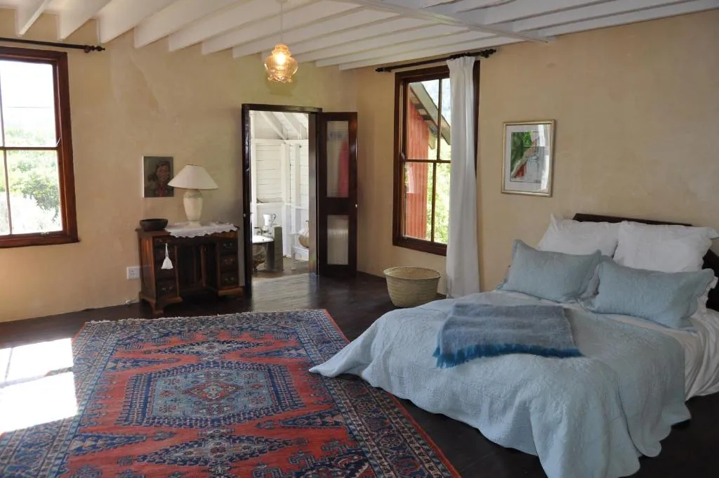 Bedroom with vaulted wood-beam ceiling, oriental rug and a door opening to the ensuite