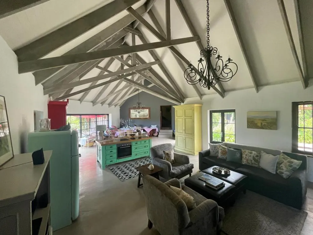 Open living room and kitchen with vaulted beams, mint-green fridge and mismatched seating