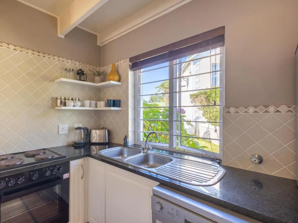 Country-style kitchen with a double sink, gas stove, and a window over the garden