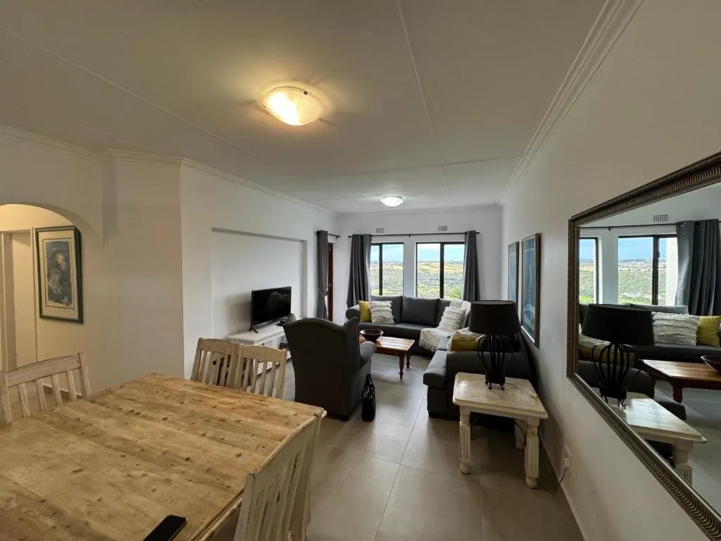 Dining table opening through an archway to the lounge, with the same hillside view beyond