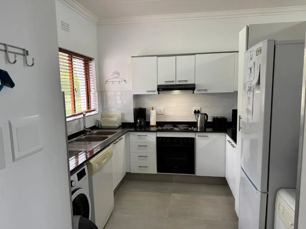 U-shaped kitchen with white cabinetry, gas stove, dishwasher and a washing machine
