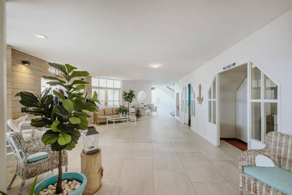 Hallway with wicker armchairs and potted plants leading past guest room doors