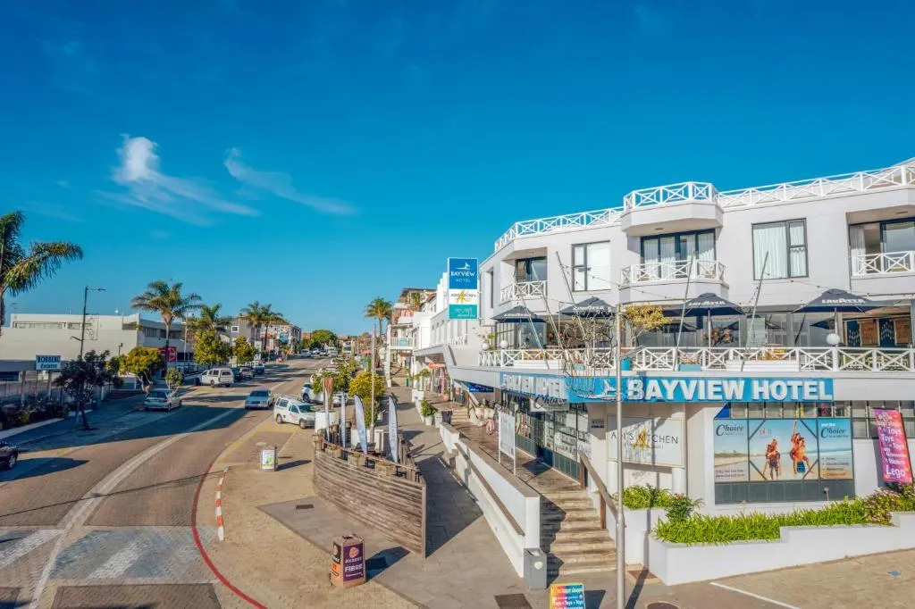 Street view of the Bayview Hotel's white balconied facade on Plettenberg Bay's main road