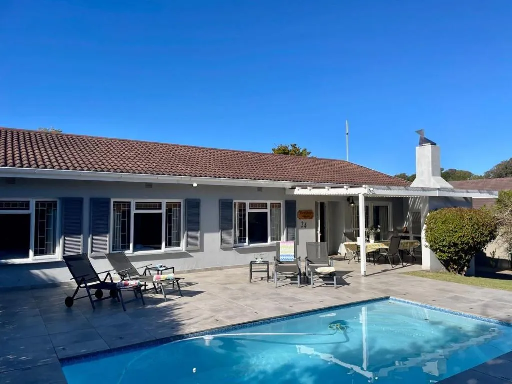 House exterior showing the covered patio, outdoor dining table, and pool from a side angle
