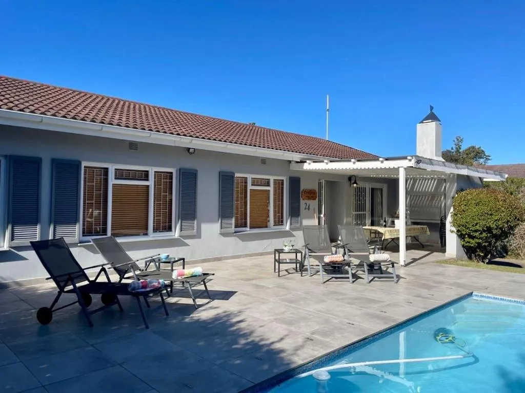 Poolside patio with sun loungers, outdoor seating, and a covered dining nook under the pergola