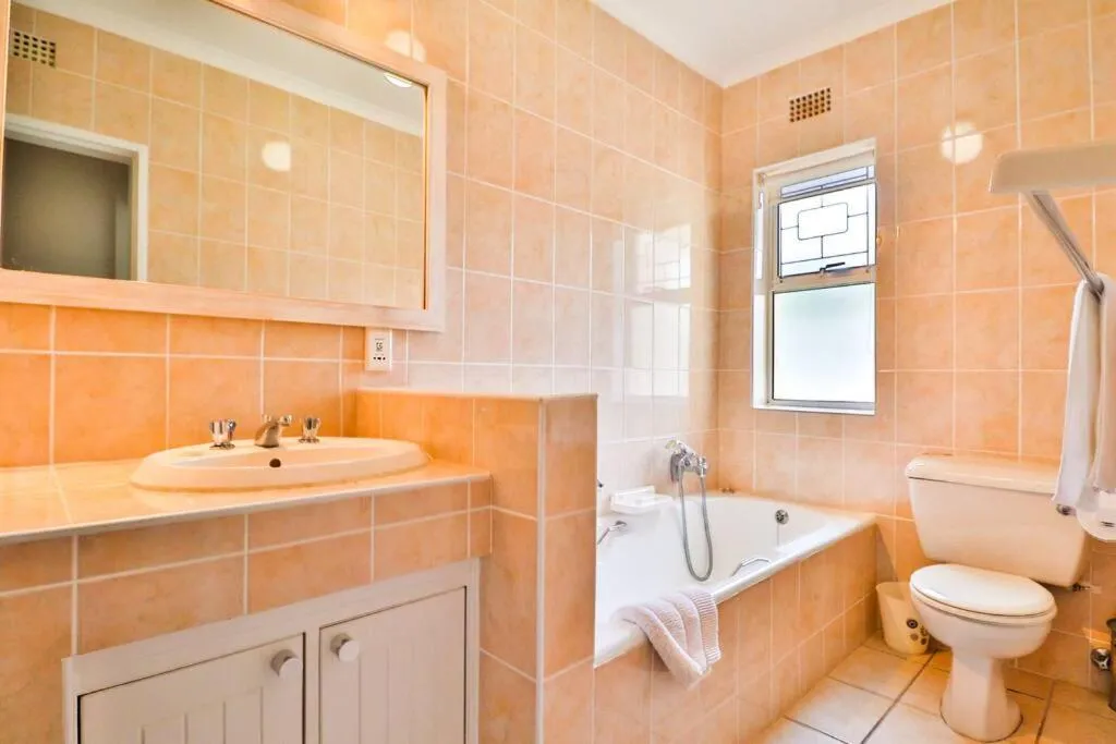 Bathroom with peach tiling, a bathtub and a separate vanity