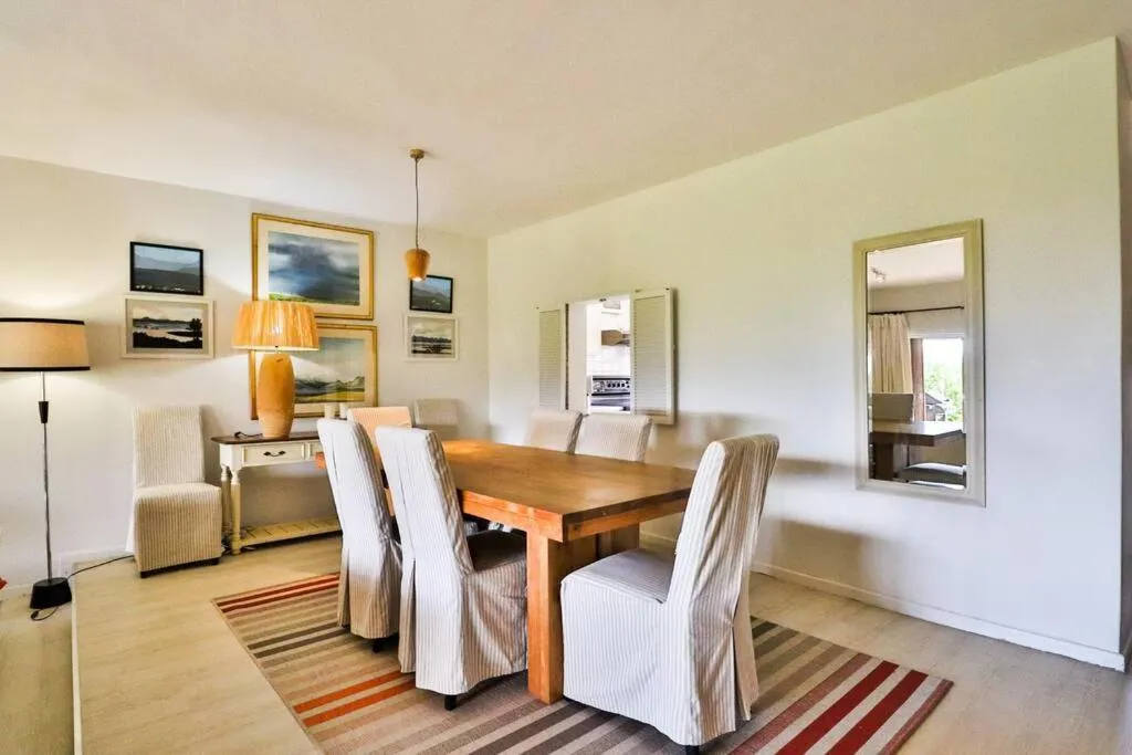 Dining room seating six at a wooden table beneath framed landscape art