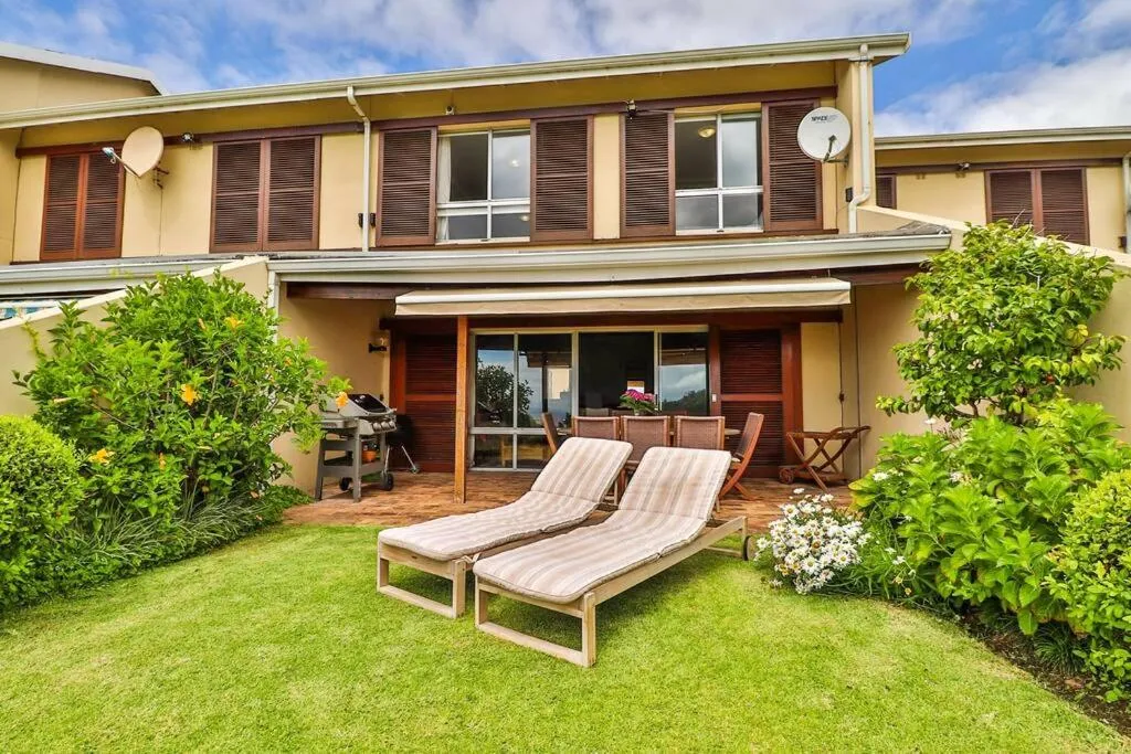 Townhouse exterior with a covered patio, gas braai and sun loungers on the lawn