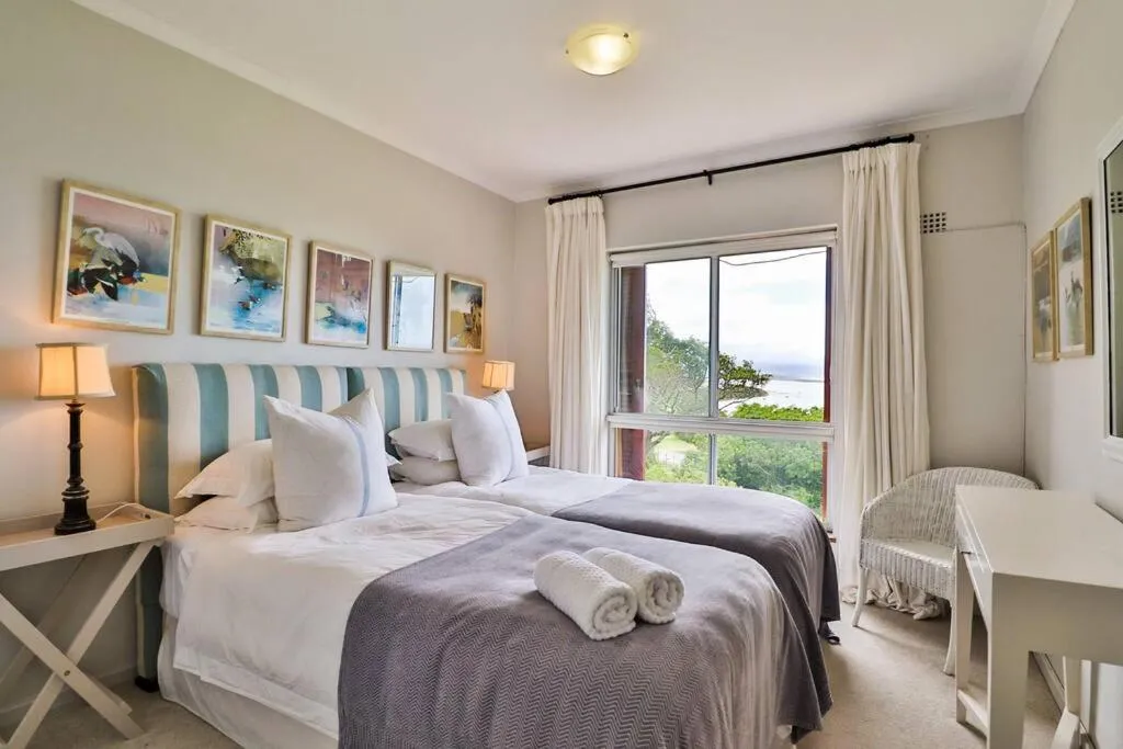 Twin bedroom with bird prints above the beds and a water view through the window