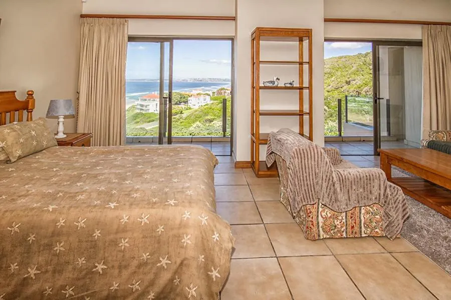 Bedroom with sliding doors onto a balcony overlooking the beach and ocean