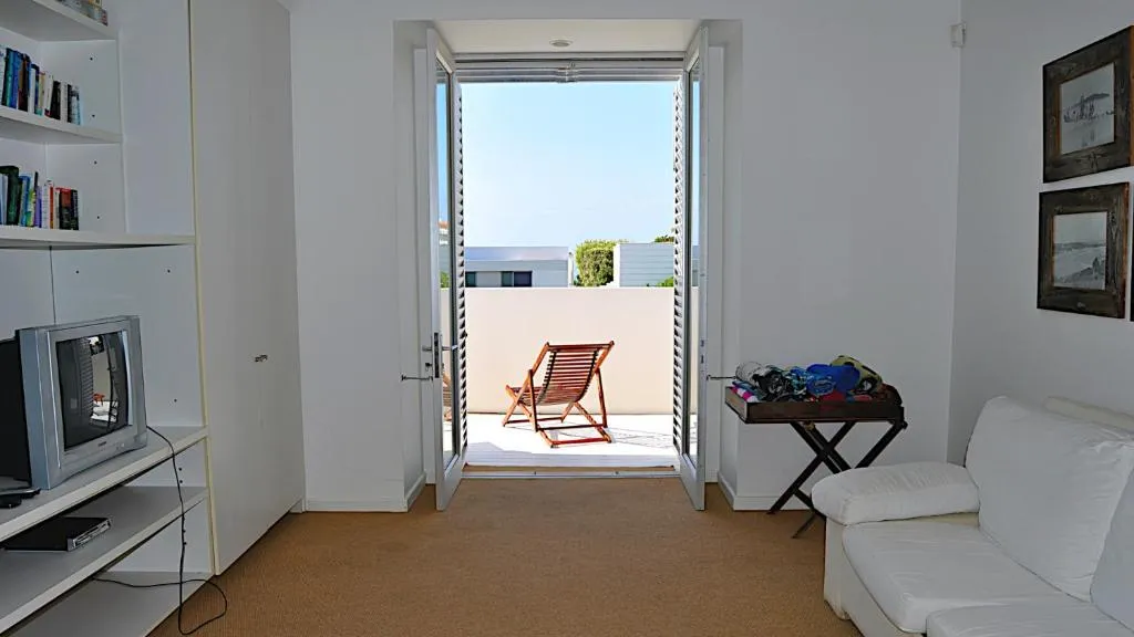 Lounge with French doors open to a small balcony with a deck chair, overlooking neighbouring rooftops