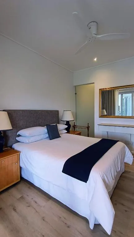 Bedroom with a grey upholstered headboard, bedside lamps and a wall mirror