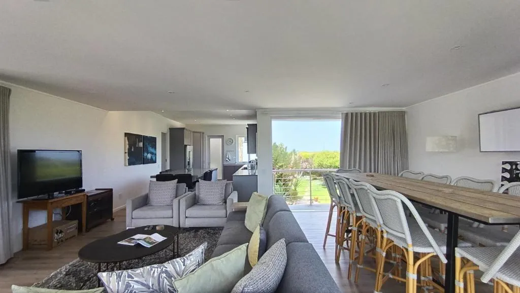 Dining and lounge area with a wall-mounted TV and long dining table