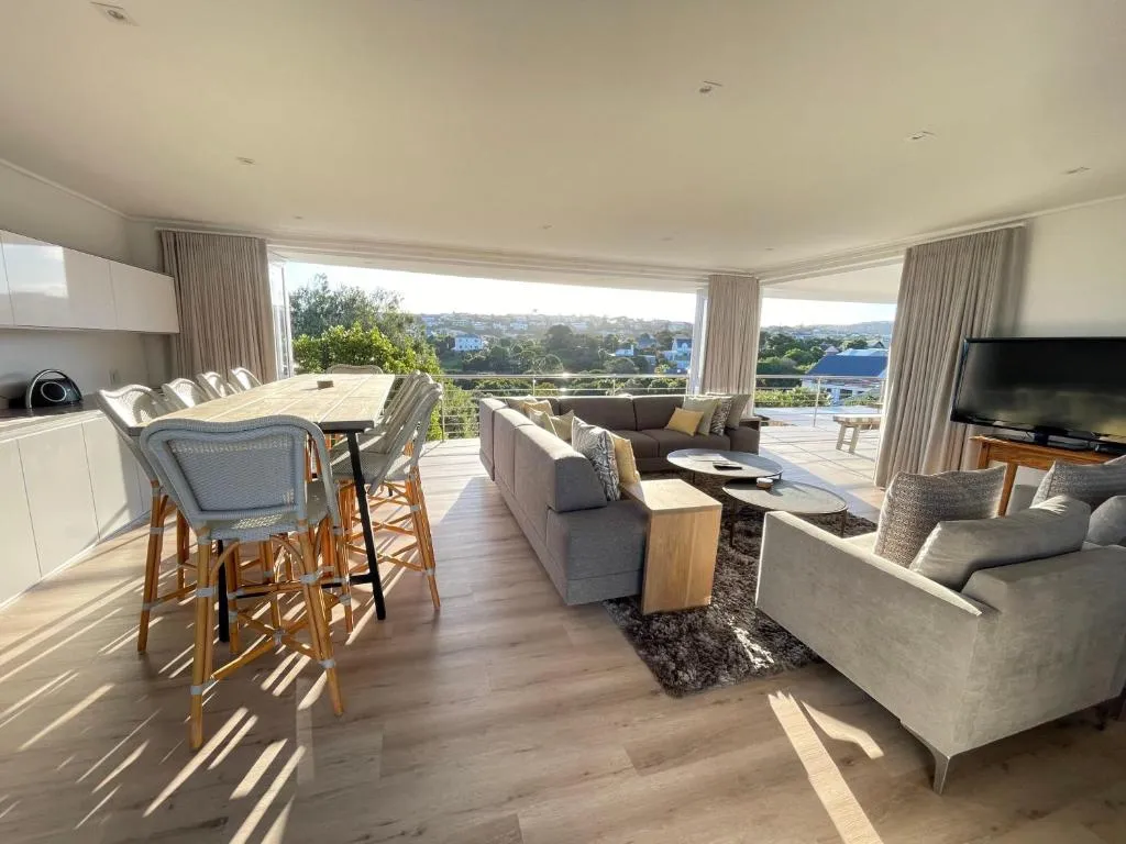 Open-plan living, dining and kitchen area with wraparound windows over the town and hills