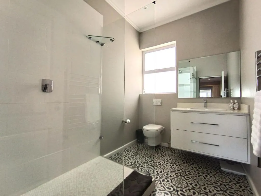 En-suite bathroom with walk-in glass shower, patterned tile floor and floating vanity