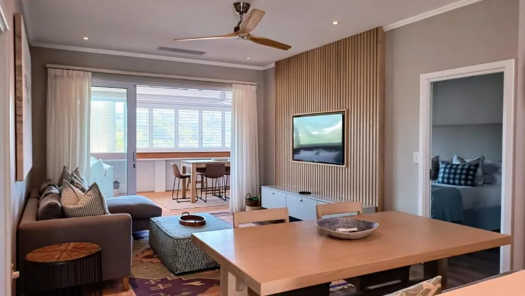Dining table in the living area with wall-mounted TV and view through to the bedroom