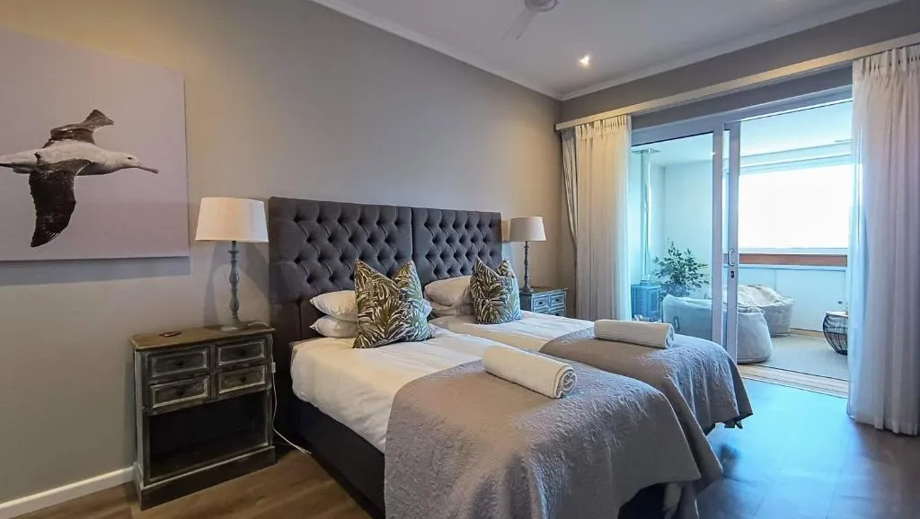 Twin bedroom with tufted headboards and sliding doors opening onto a private balcony