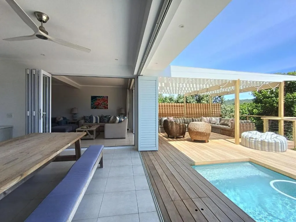 Open dining table and bench seating flow onto the pool deck and lounge through folding glass doors