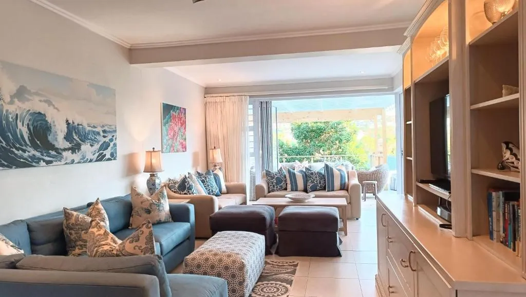 Second lounge with blue sofas, a wave-themed painting and doors opening onto a garden pergola
